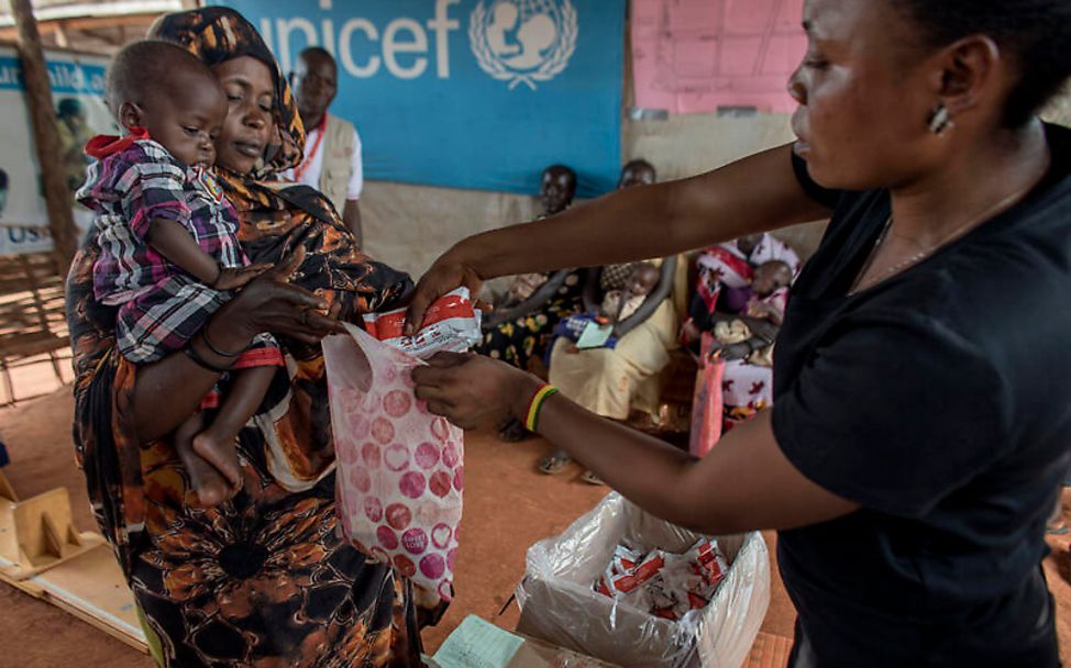 Südsudan: Eine UNICEF-Helferin gibt Erdnusspaste an eine Mutter mit Kind aus