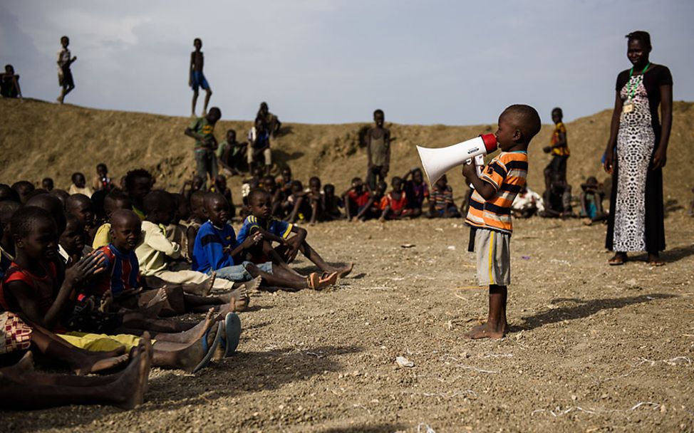 Südsudan: Ein Junge singt bei einem Event in einem child-friendly space in ein Megaphon.