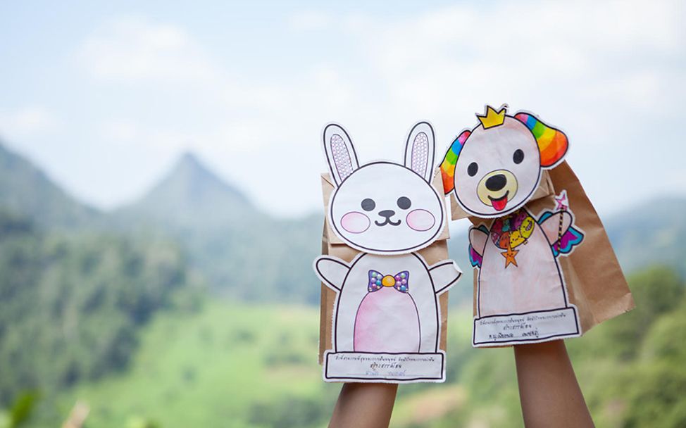 Thailand: Zwei Kinder spielen mit selbstgebastelten Handpuppen aus Papier.