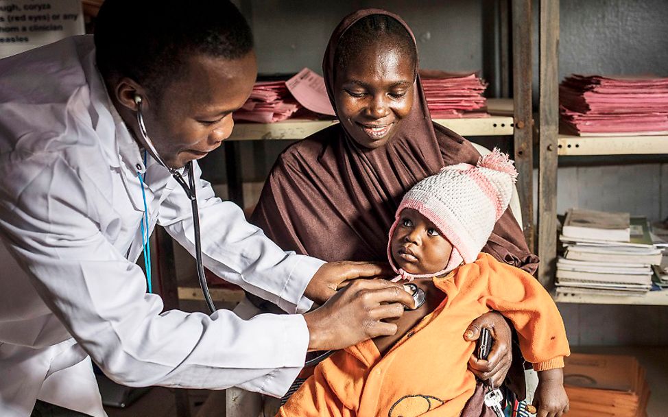 Nigeria: Ein Gesundheitshelfer untersucht den dreijährigen Jorim, der auf dem Schoss seiner Mutter sitzt.