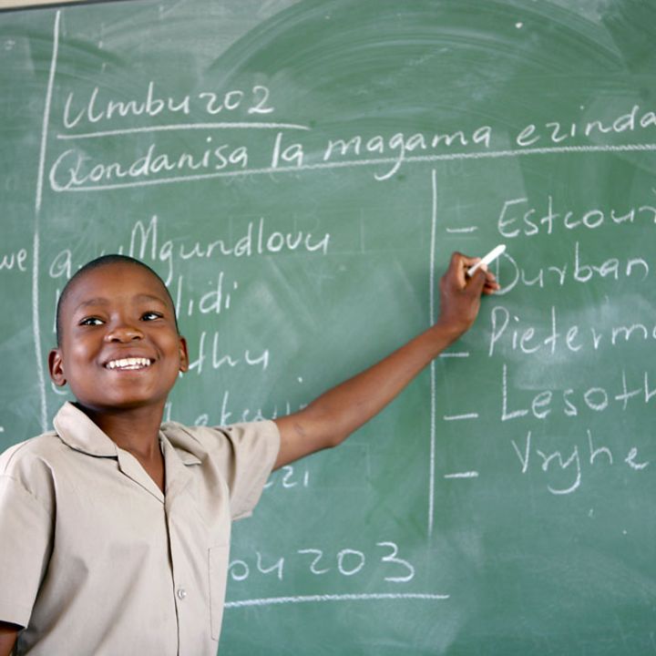Schulen in Afrika: Ein Junge steht in einem Klassenzimmer an einer Tafel. 