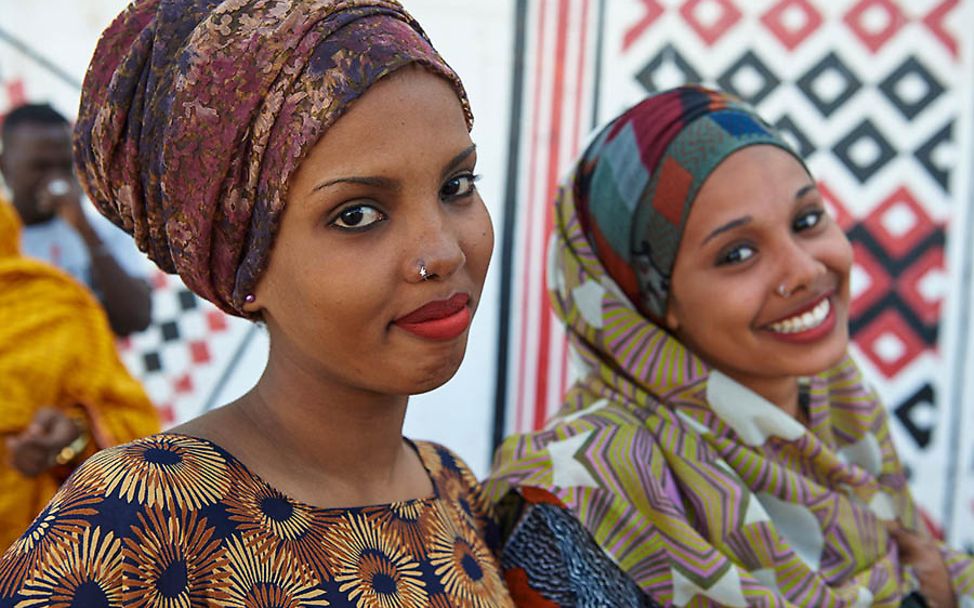 Dschibuti: Zwei junge Frauen mit bunten Kopftüchern lächeln in die Kamera.