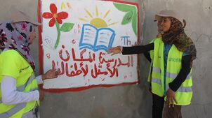 Jordanien: Muzoon und zwei weitere UNICEF-Helfer betrachten ein Bild zum Thema Schulbildung.