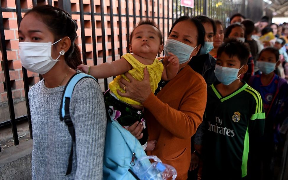 Kambodscha: Menschen mit Gesichtsmasken warten in einer Schlange.