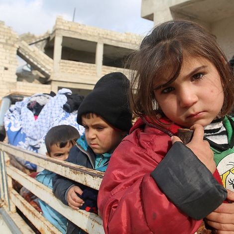 Syrien: Kinder sitzen auf der Ladefläche eines Trucks, der durch eine zerstörte Stadt in Idlib fährt.