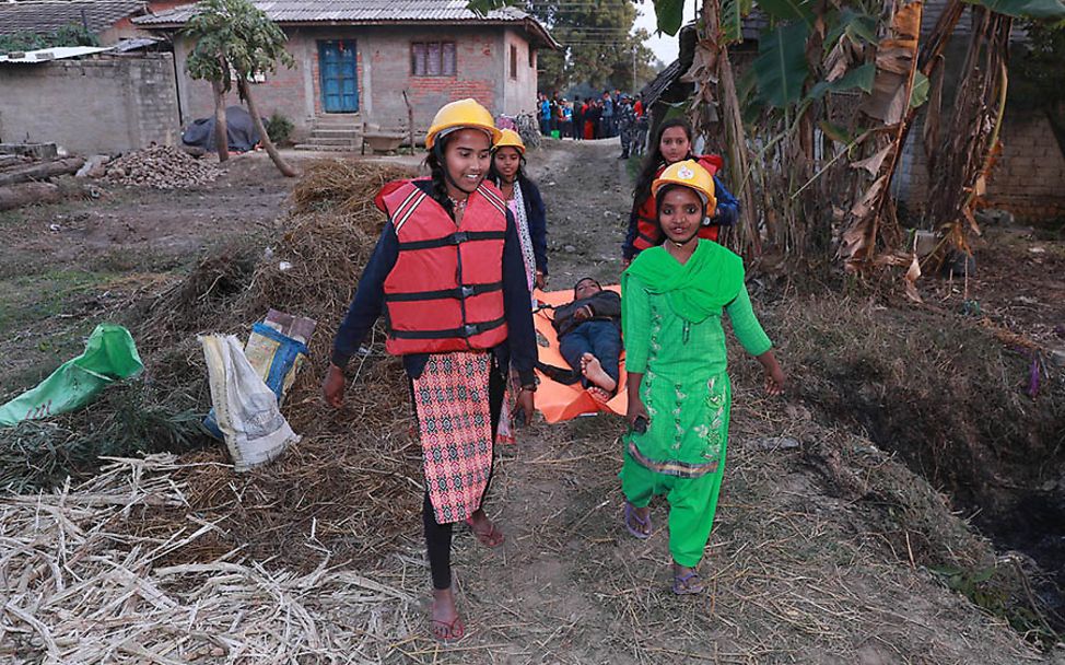 Nepal: Vier Kinder befördern einen Mann auf einer Trage.