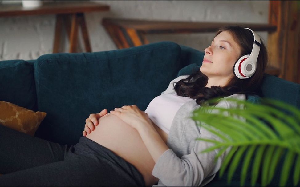 Musik in der Schwangerschaft: Eine Frau entspannt mit Kofhhörern.
