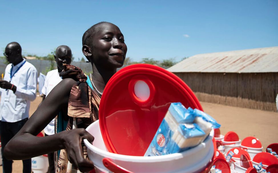 Corona: Im Südsudan bekommt eine Frau Wassereimer und Seife von UNICEF