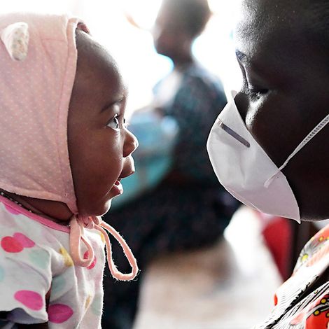 Elfenbeinküste: Die kleine Christelle schaut sich die Schutzmaske ihrer Mutter an.