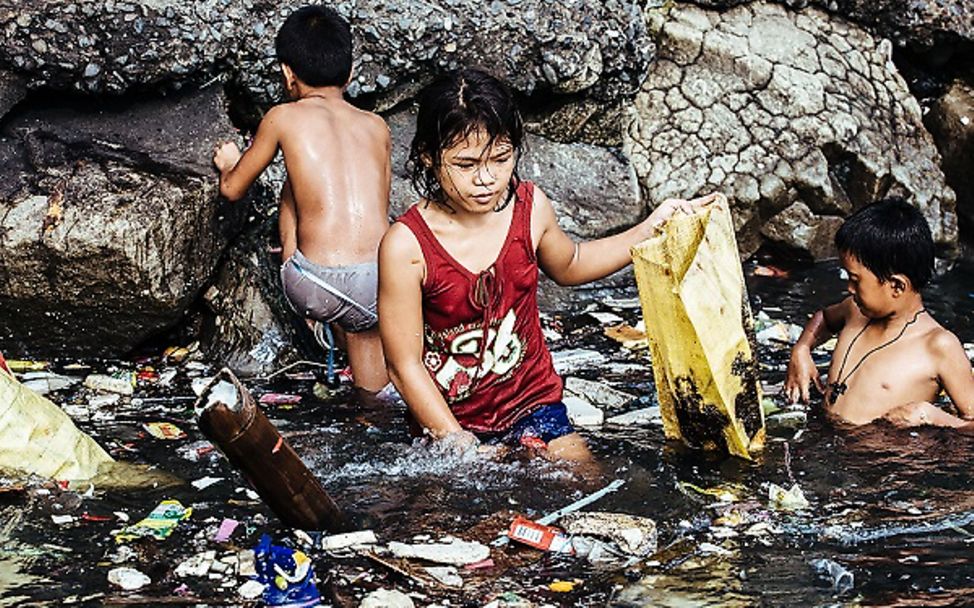 Philippinen: Wenie und ein Junge stehen im dreckigen Wasser.