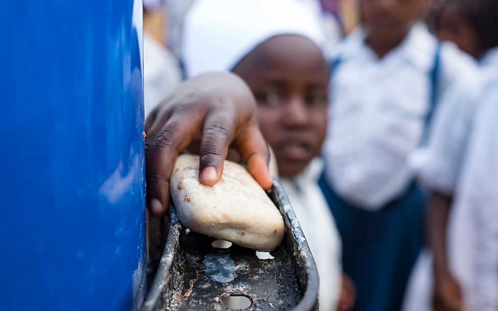 Kongo: Ein junger Schüler wäscht seine Hände mit Seife.