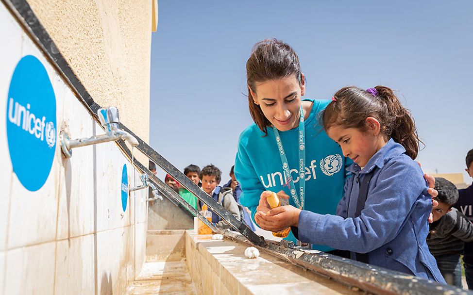 UNICEF-Helferin zeigt einem Mädchen in Jordanien, wie Händewaschen richtig geht.