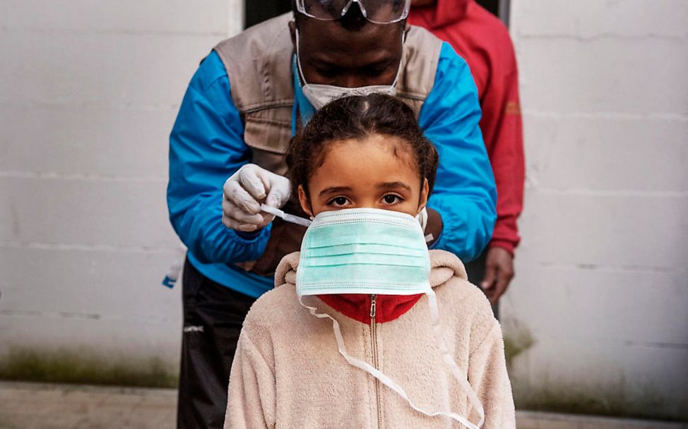 Corona in Rom: UNICEF-Gesundheitshelfer bindet Francesca die Maske um