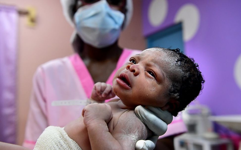 Covid-19-Pandemie: Ein Neugeborenes in den Händen einer Hebamme