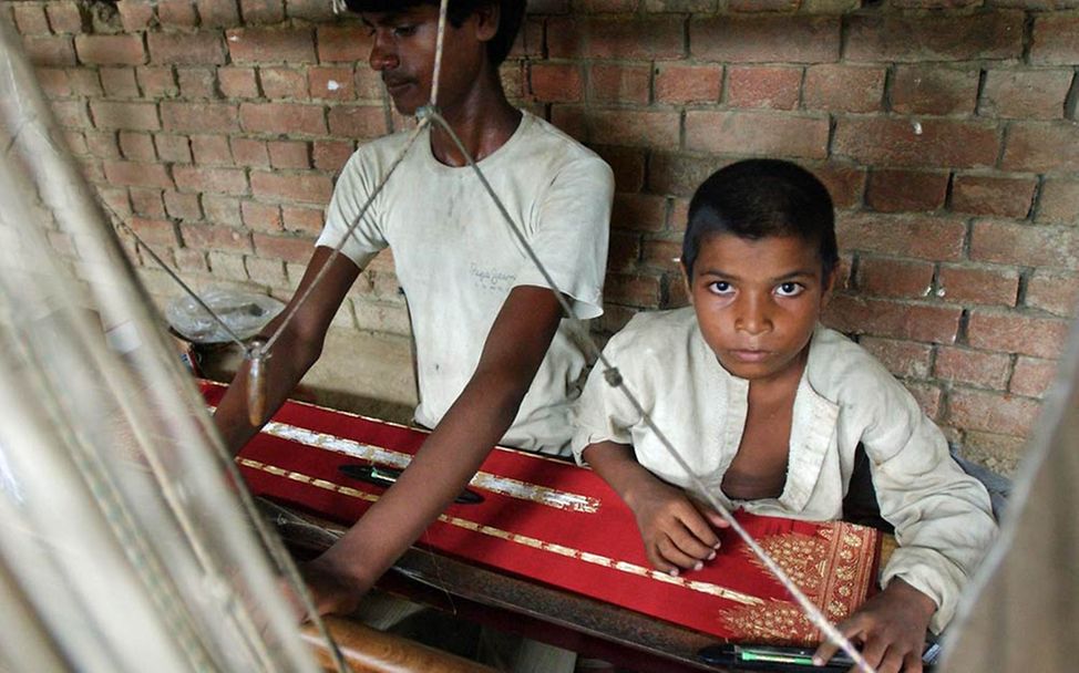 Kinderarbeit in Indien: Zwei Kinder arbeiten für ein paar Rupien in einer Fabrik der indischen Textilindustrie.