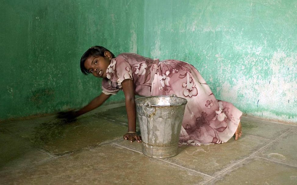 Kinderarbeit in Indien: Ein Mädchen schrubbt einen Boden. Mädchen arbeiten in indischen Haushalten für einen Hungerlohn.