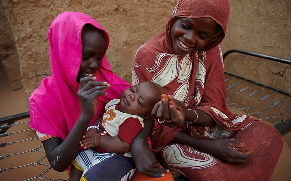 Flüchtlingslager Sudan: Mädchen hält ein Baby in den Armen.