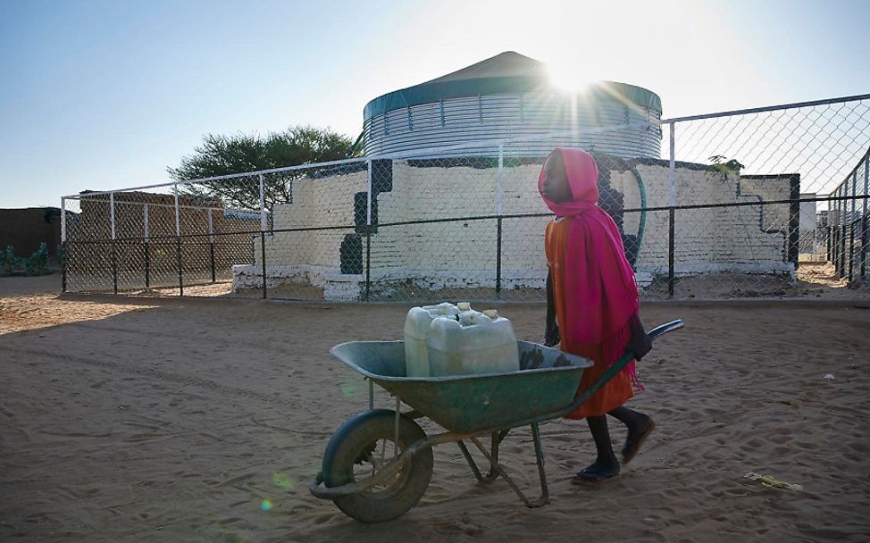 Sudan: Mädchen holt sich Trinkwasser mit Schubkarre.