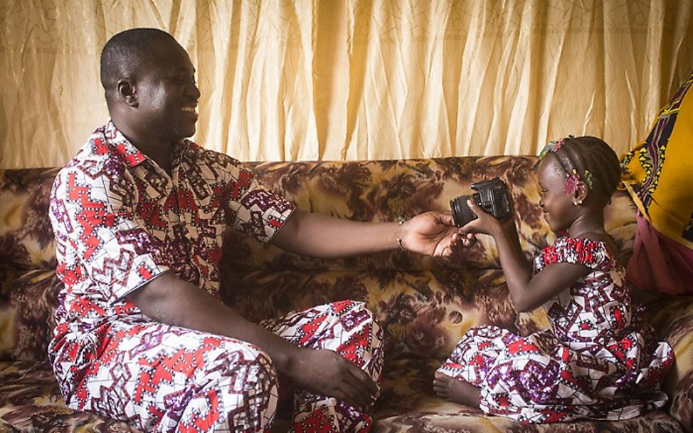 Mali: Tochter sitzt neben ihrem Vater auf der Couch.