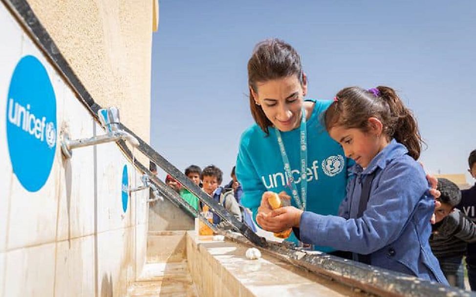 Eine UNICEF-Helferin hilft einem Mädchen beim Händewaschen. © UNICEF/UNI313299/Matas