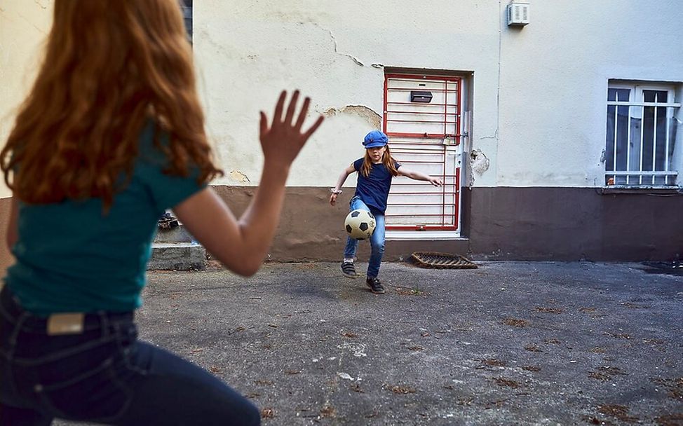 Sport im Alltag: Zwei Mädchen spielen draußen Fußball.