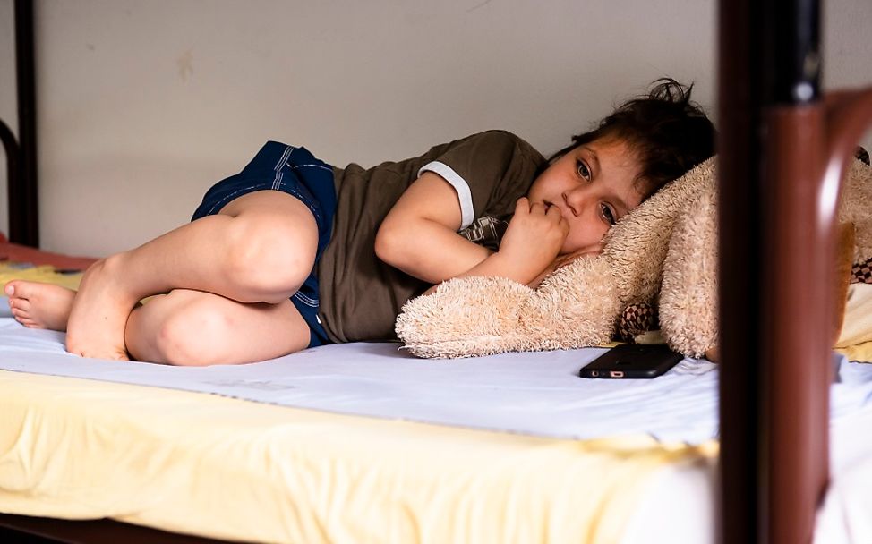 Flüchtlingsunterkunft: Ein Junge liegt allein im Bett.