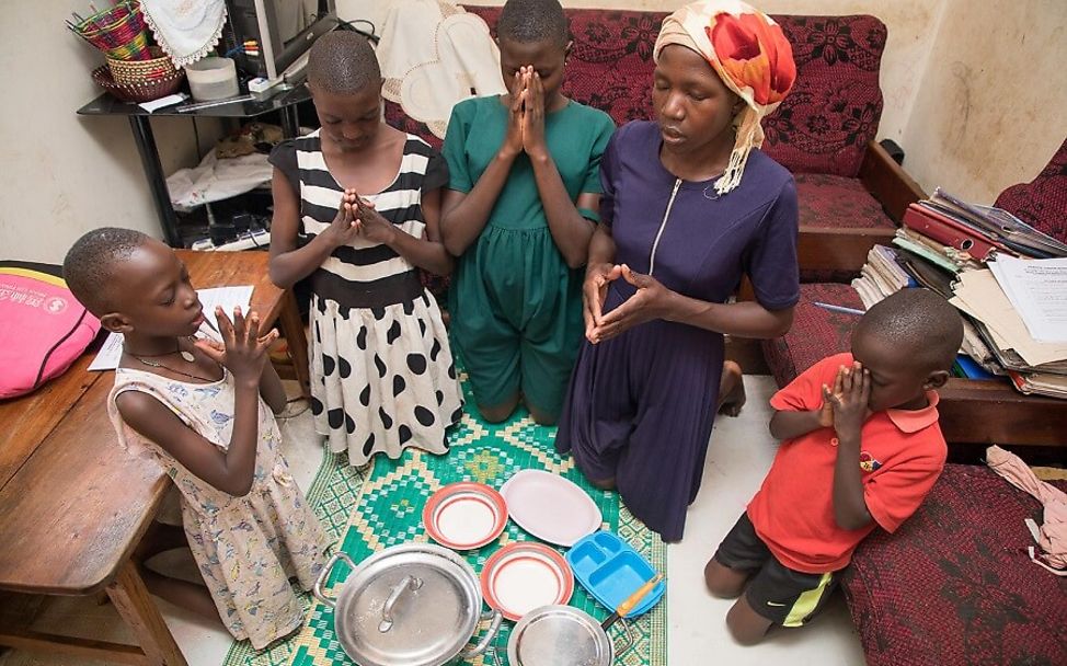Corona Uganda: Familie betet vor dem Essen.