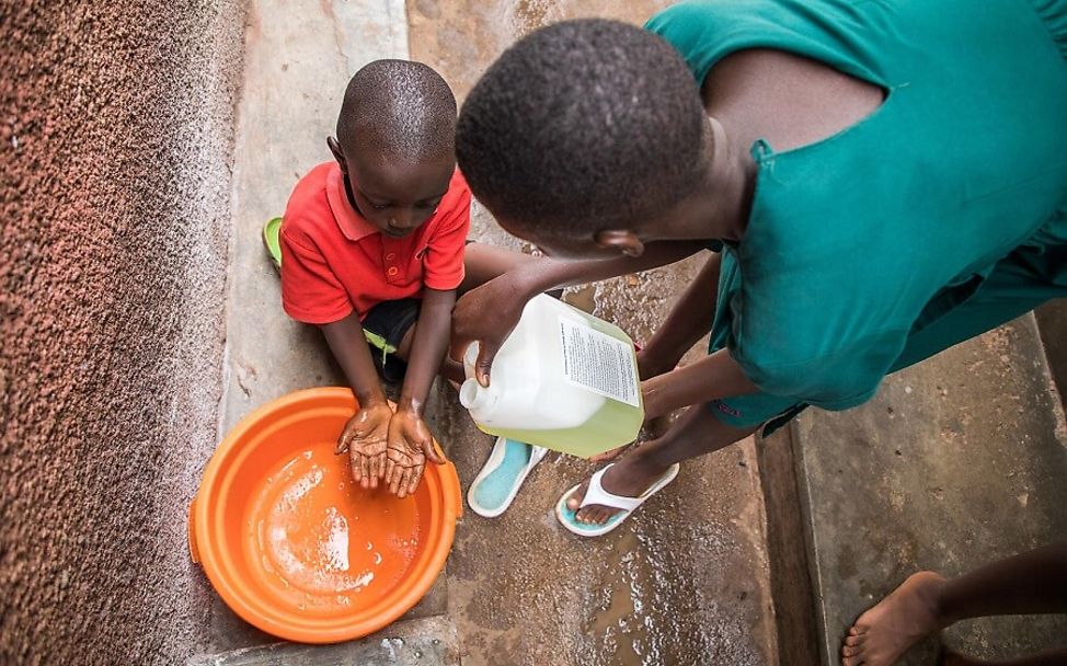 Corona Uganda: Sharon hilft ihrem Bruder beim Händewaschen.