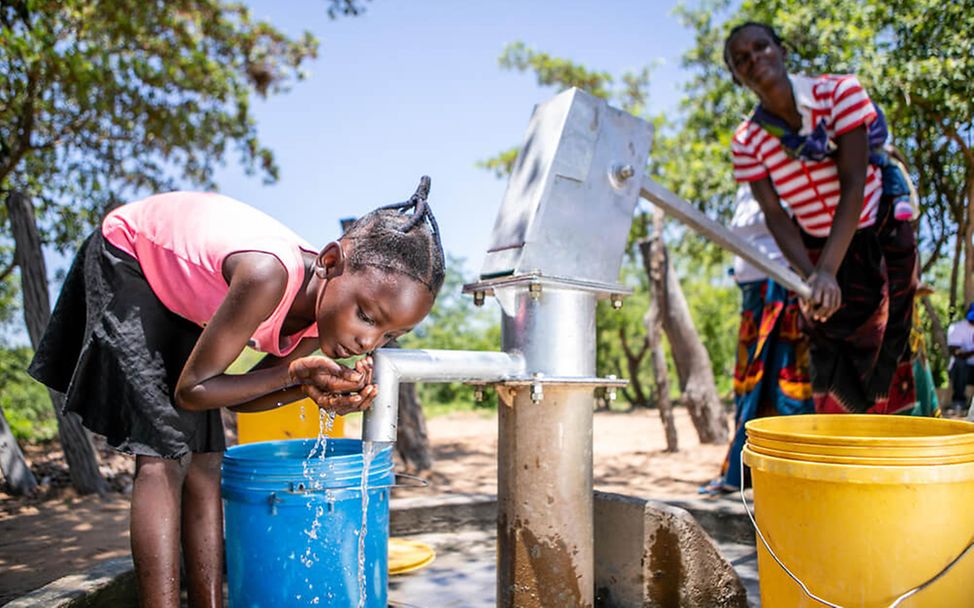 Dürre in Sambia 2020: Ein Mädchen trinkt Wasser aus einem Brunnen