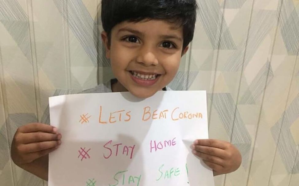 Corona in Pakistan: Ein Junge mit einer Stay Safe-Botschaft