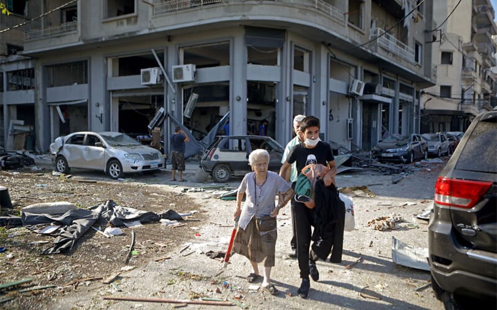 Libanon: Explosion in Beirut: Ein Junge hilft einer älteren Frau durch die Trümmer