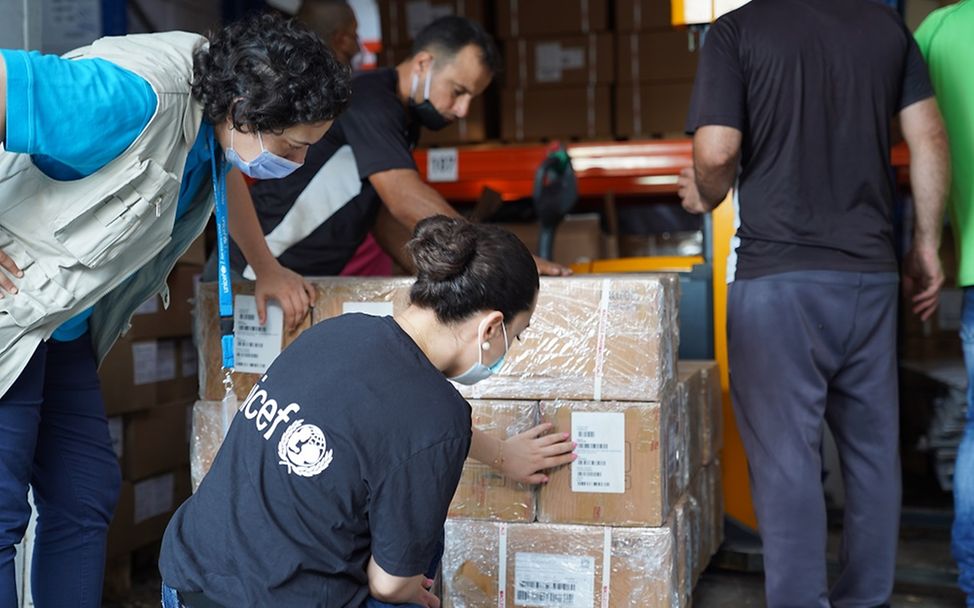 UNICEF-Mitarbeiterin untersucht einen Karton mit Hilfsgütern auf Schäden