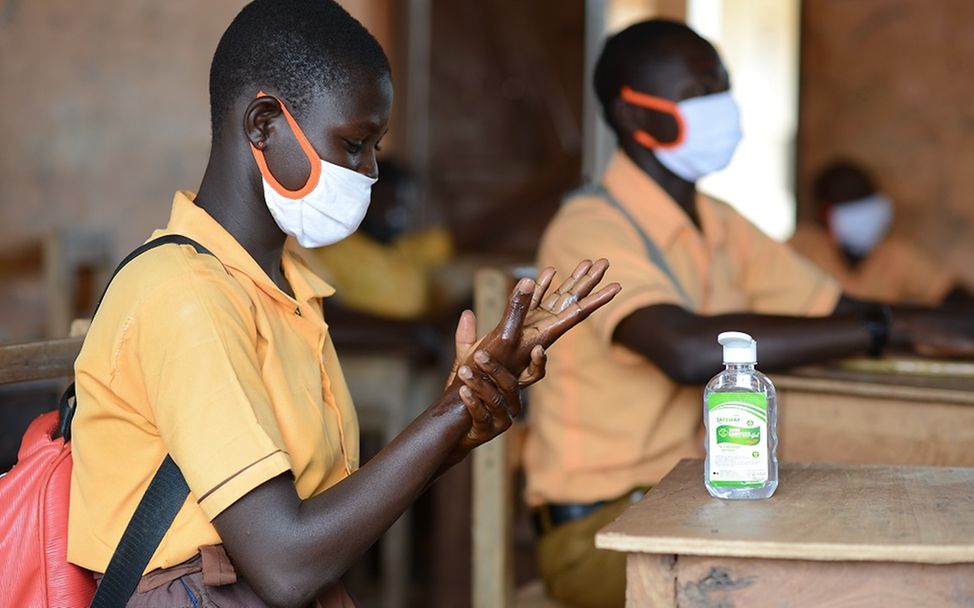 Schüler aus Ghana trägt Schutzmaske und desinfiziert sich die Hände.