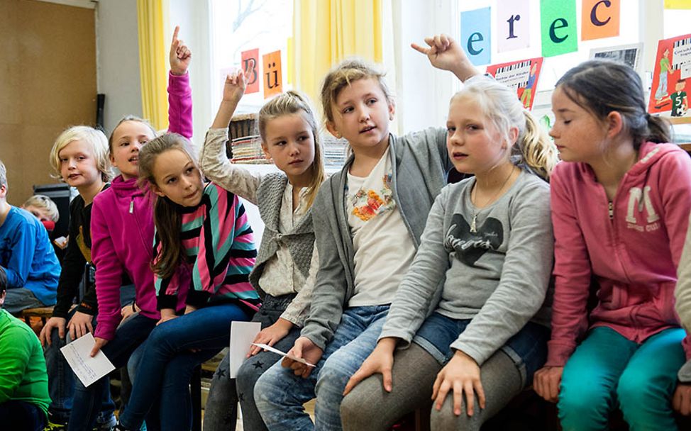 IKEA Kinderrechte: Schülerinnen zeigen auf, um sich zu beteiligen.