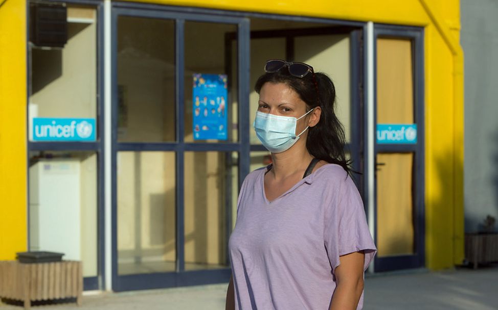 Sophia steht mit Mundschutz vor dem Eingang des von UNICEF unterstützten Kinderzentrums auf Lesbos.
