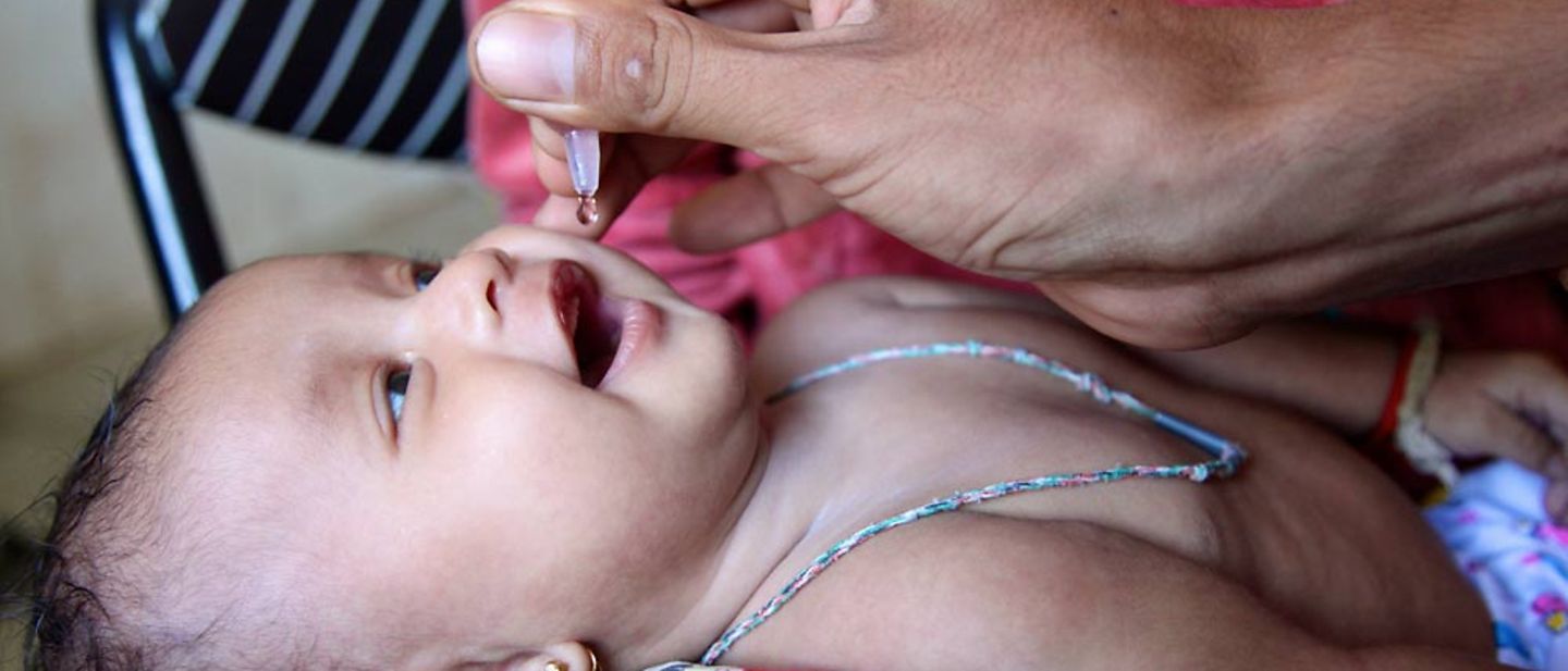 Ein Baby in Kambodscha erhält ein paar Tropfen einer oralen Impfung.