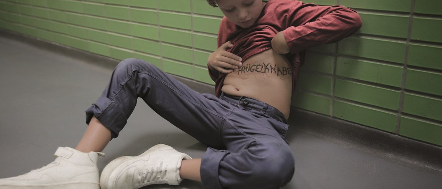 Gewalt hinterlässt Spuren: Ein Junge schaut auf seinen Bauch.