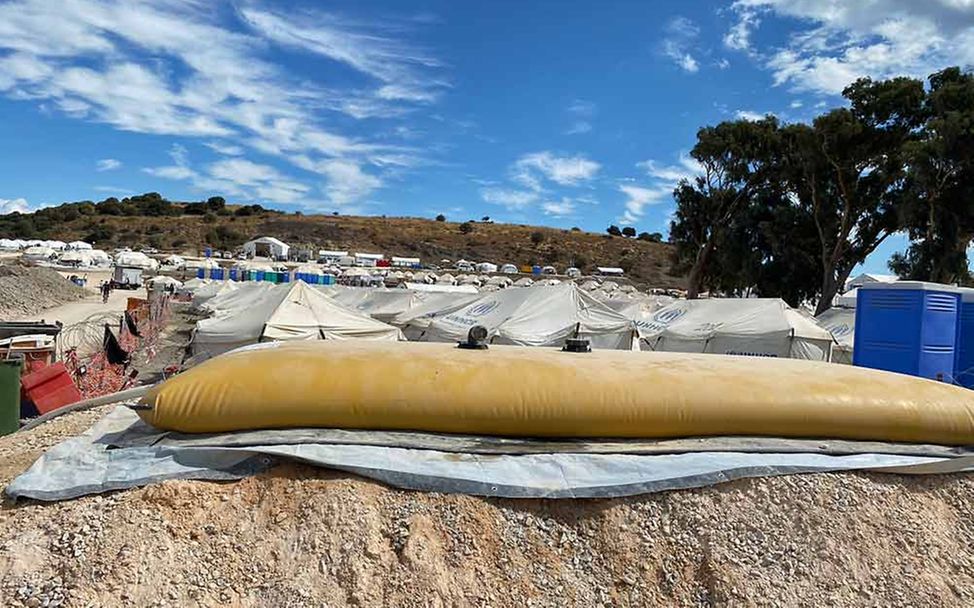 Ein großer flacher Wassertank aus Plastik mitten im Flüchtlingslager Kara Tepe.