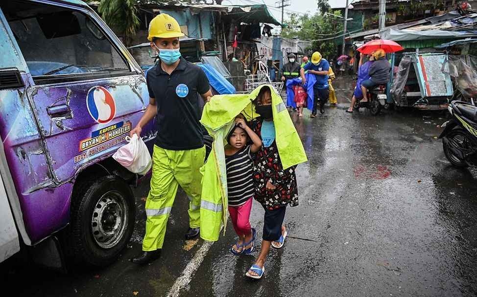 Taifun Goni: Ein Rettungshelfer geleitet zwei Kinder zum Evakuierungsfahrzeug.