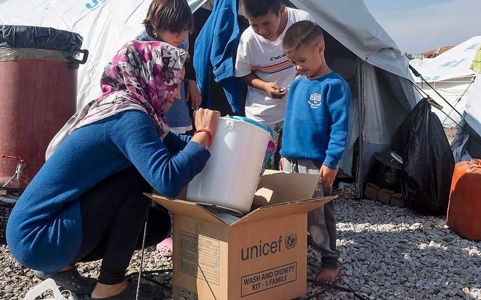 Eine Familie im Flüchtlingscamp Kara Tepe packt eine Kiste mit UNICEF-Hilfsgütern aus.