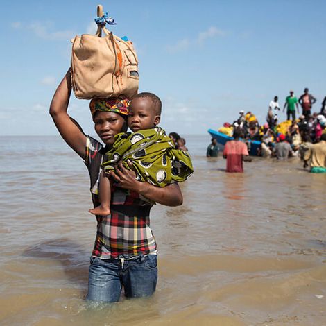 Idai Mosambik: Eine Frau trägt ein Kind durch Wasser