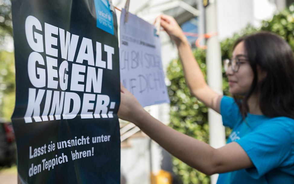 Gewalt gegen Kinder: Eine UNICEF-Helferin hängt Plakate auf.