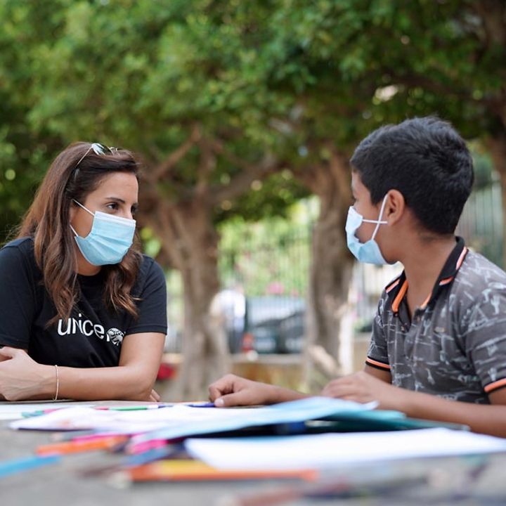 Eine UNICEF-Mitarbeiterin unterhält sich intensiv mit einem Jungen. 