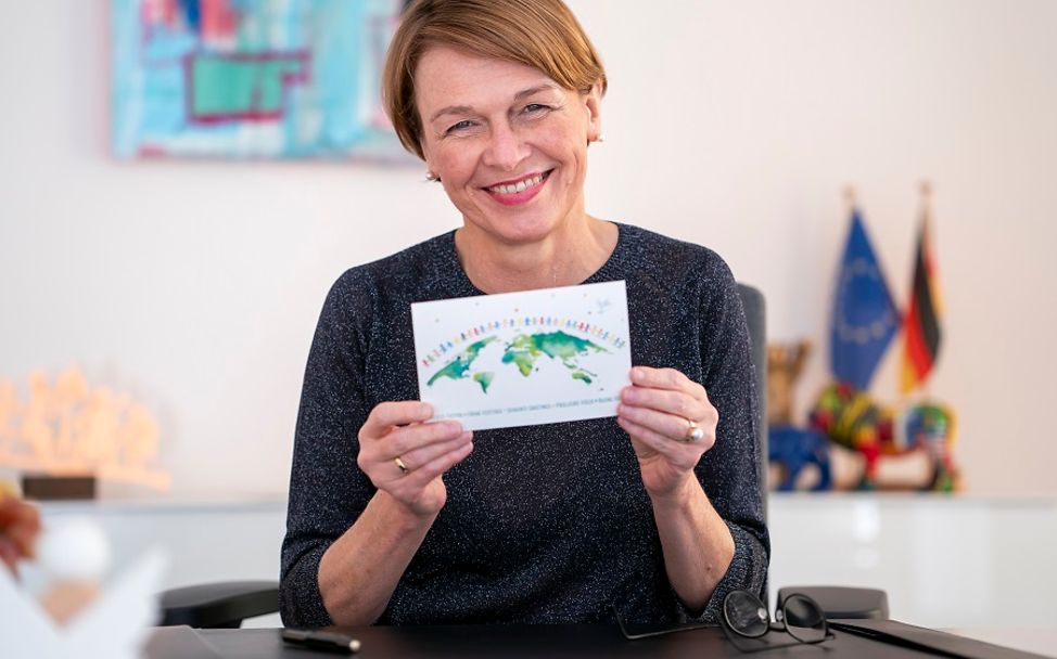 Elke Büdenbender präsentiert UNICEF-Karte in die Kamera.