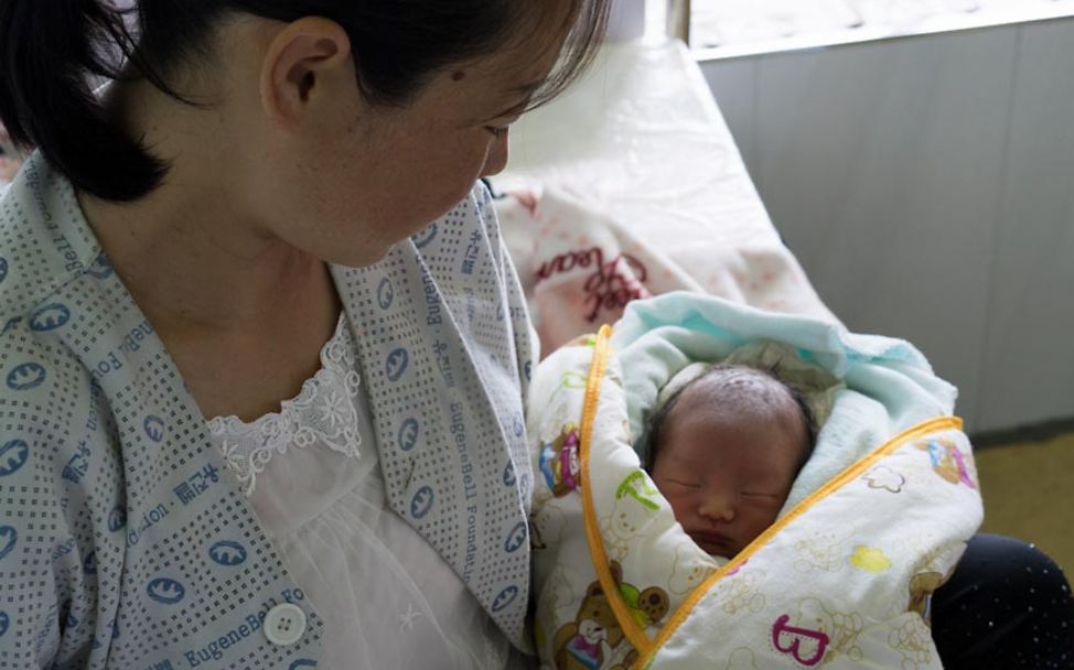 Mangelernährung in Nordkorea: Eine Mutter hält ihr in Decken eingehülltes Neugeborenes auf dem Arm. 