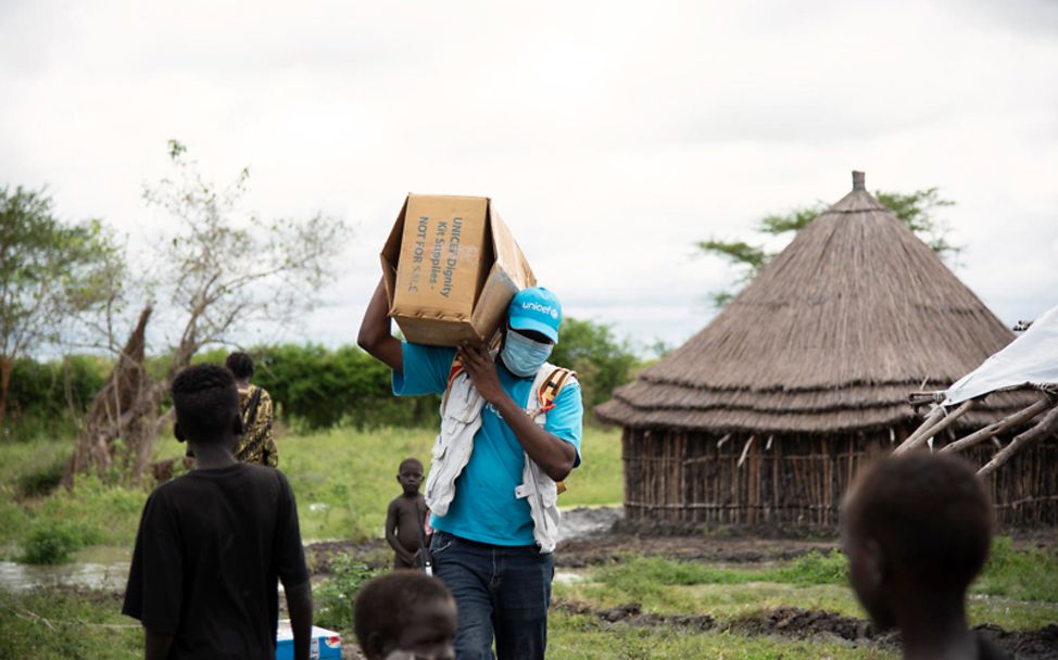 Südsudan: Ein UNICEF-Helfer bringt ein Paket mit Hilfsgütern ins Dorf