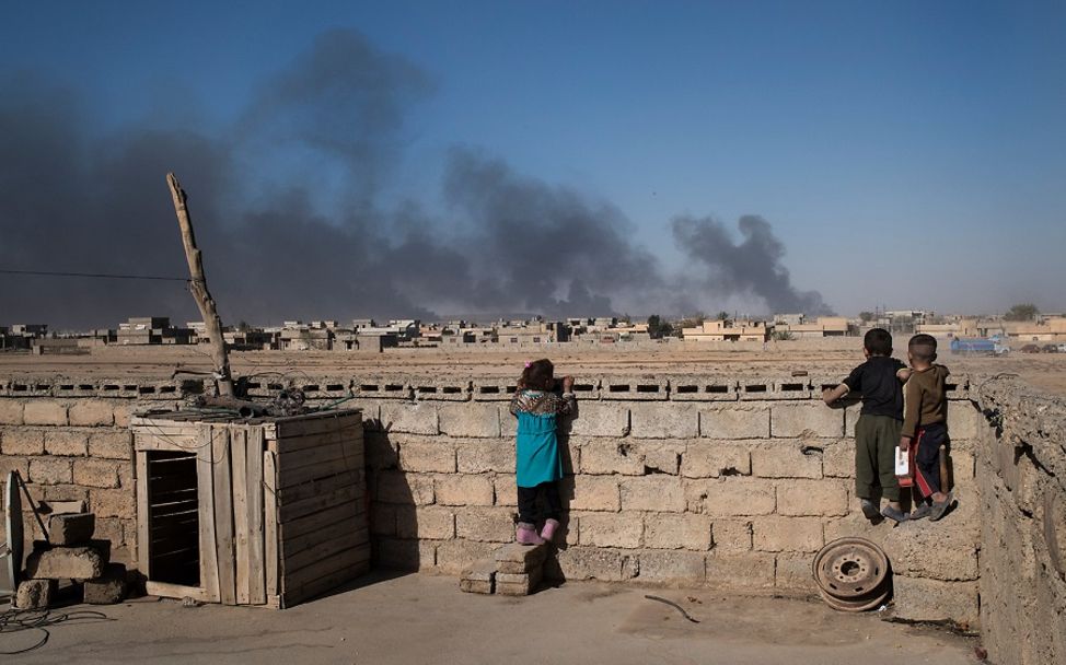 Irak 2016: Kinder blicken auf Feuer des Kriegs am Horizont.