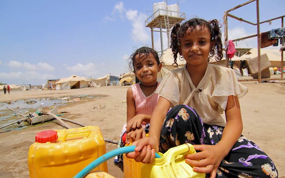 Jemen: Zwei Mädchen füllen an einer Wasserstelle in einem Flüchtlingscamp ihre Wasserkanister. 