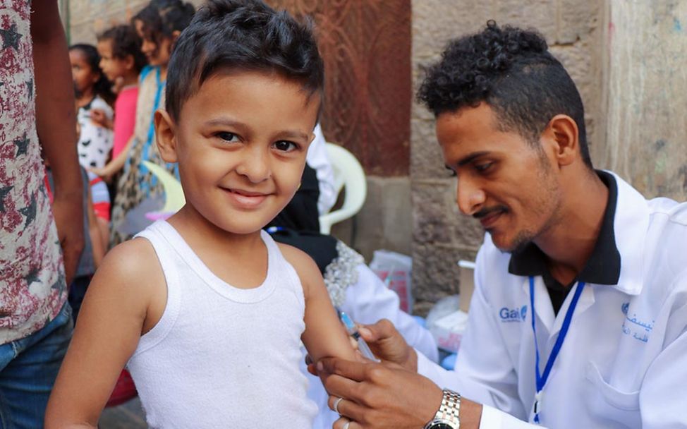 Ein Junge im Jemen wird während einer UNICEF-Impfkampagne von einem Gesundheitshelfer geimpft.