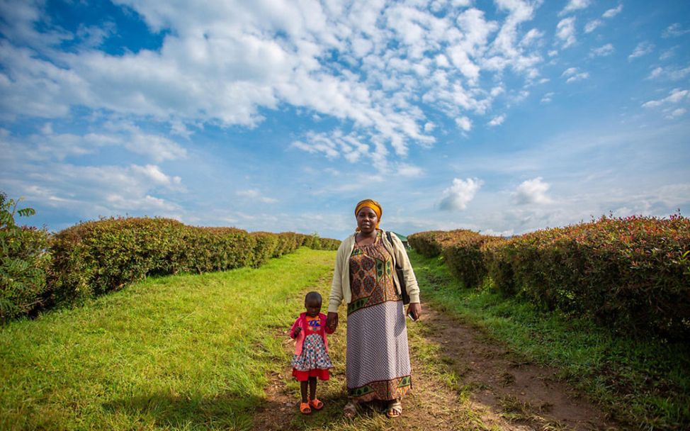 Ruanda: Mutter und Kind stehen auf einem Feld.
